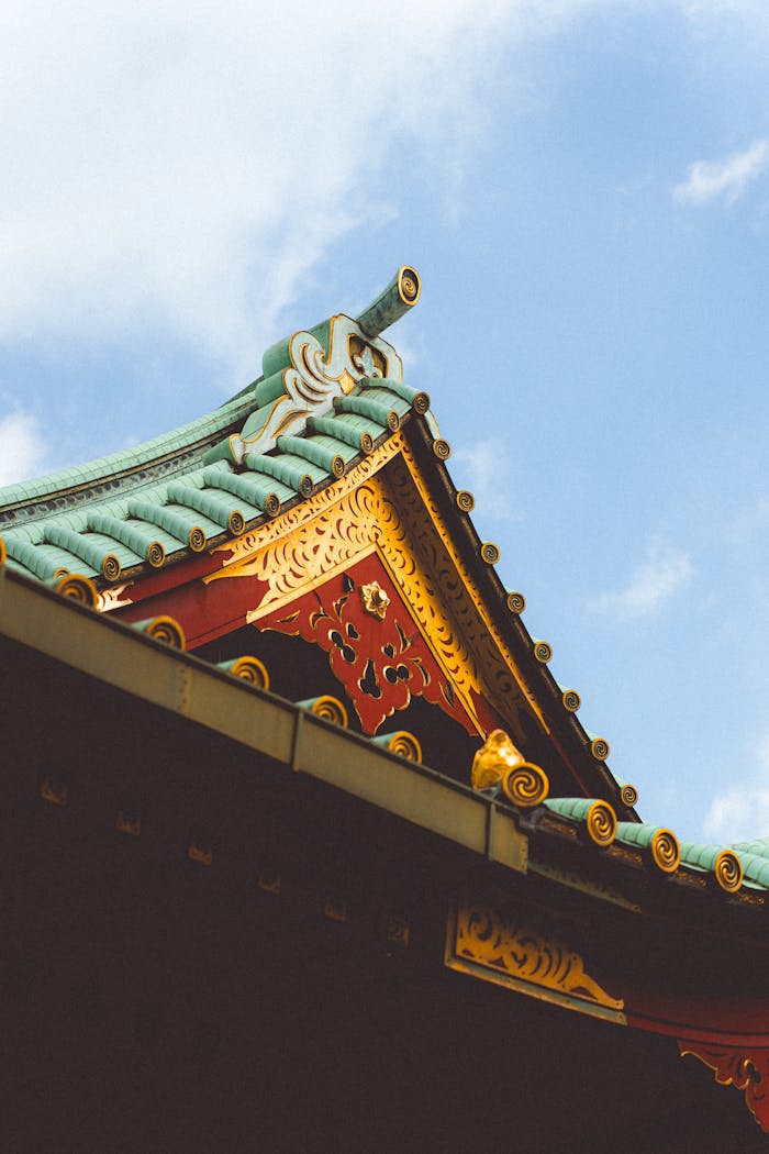 Intricate architectural details of a Japanese temple roof against a clear blue sky in Tokyo, Japan.