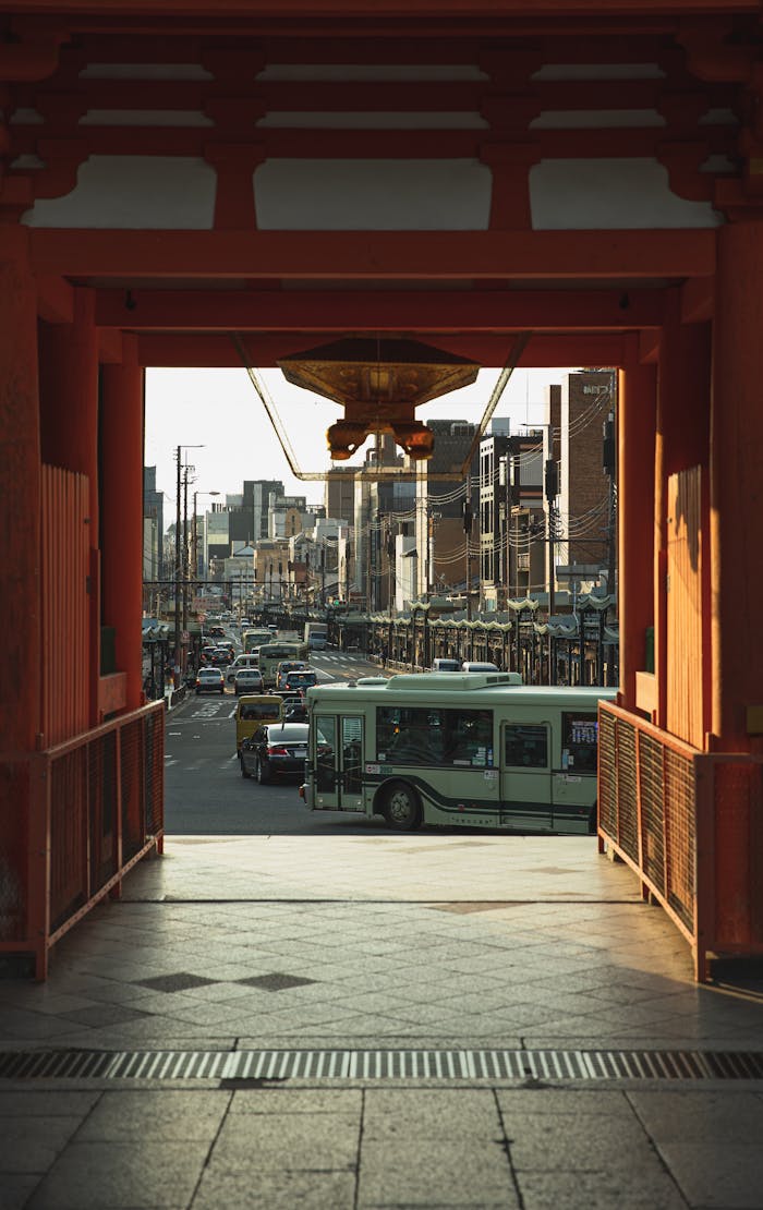 Through red gates of ancient Yasaka Shrine of various vehicles driving on road in Kyoto district