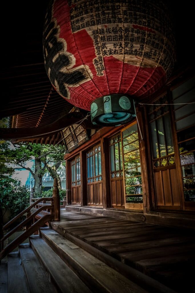 Wooden steps leading to a Japanese temple adorned with a paper lantern.